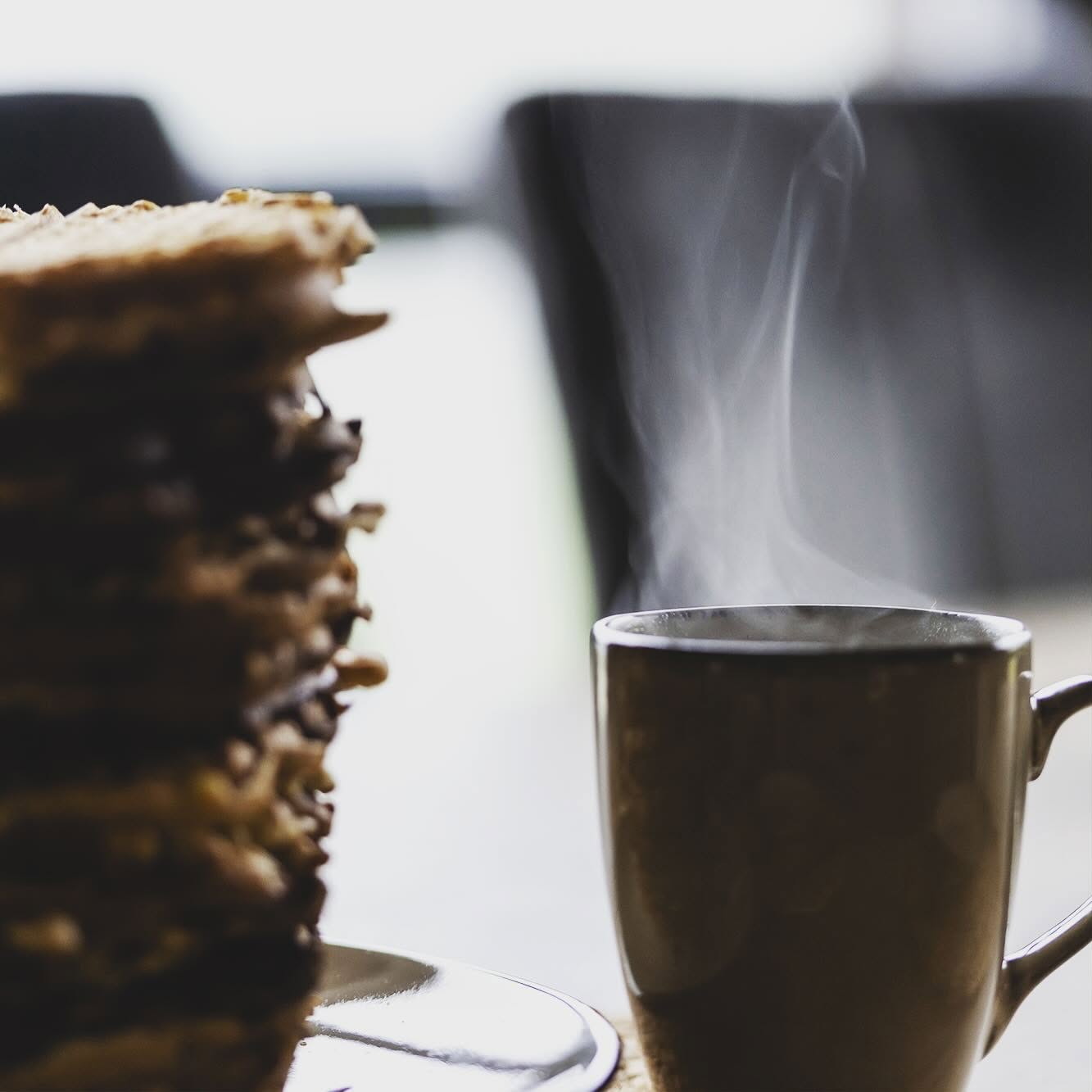 En kopp kaffe med damp ved siden av en stabel vafler